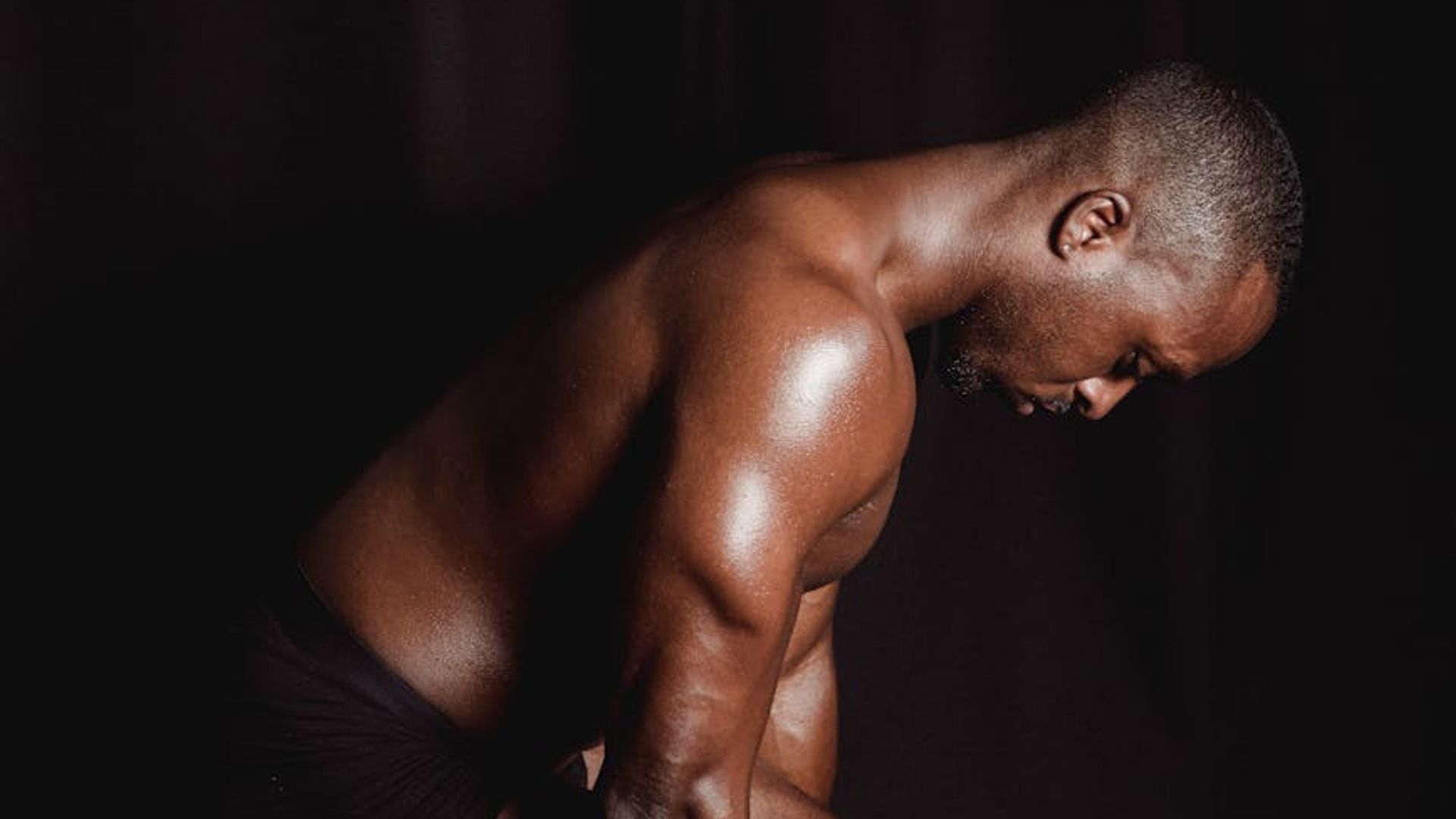 Man performing a controlled strength exercise in a minimalist dark gym.
